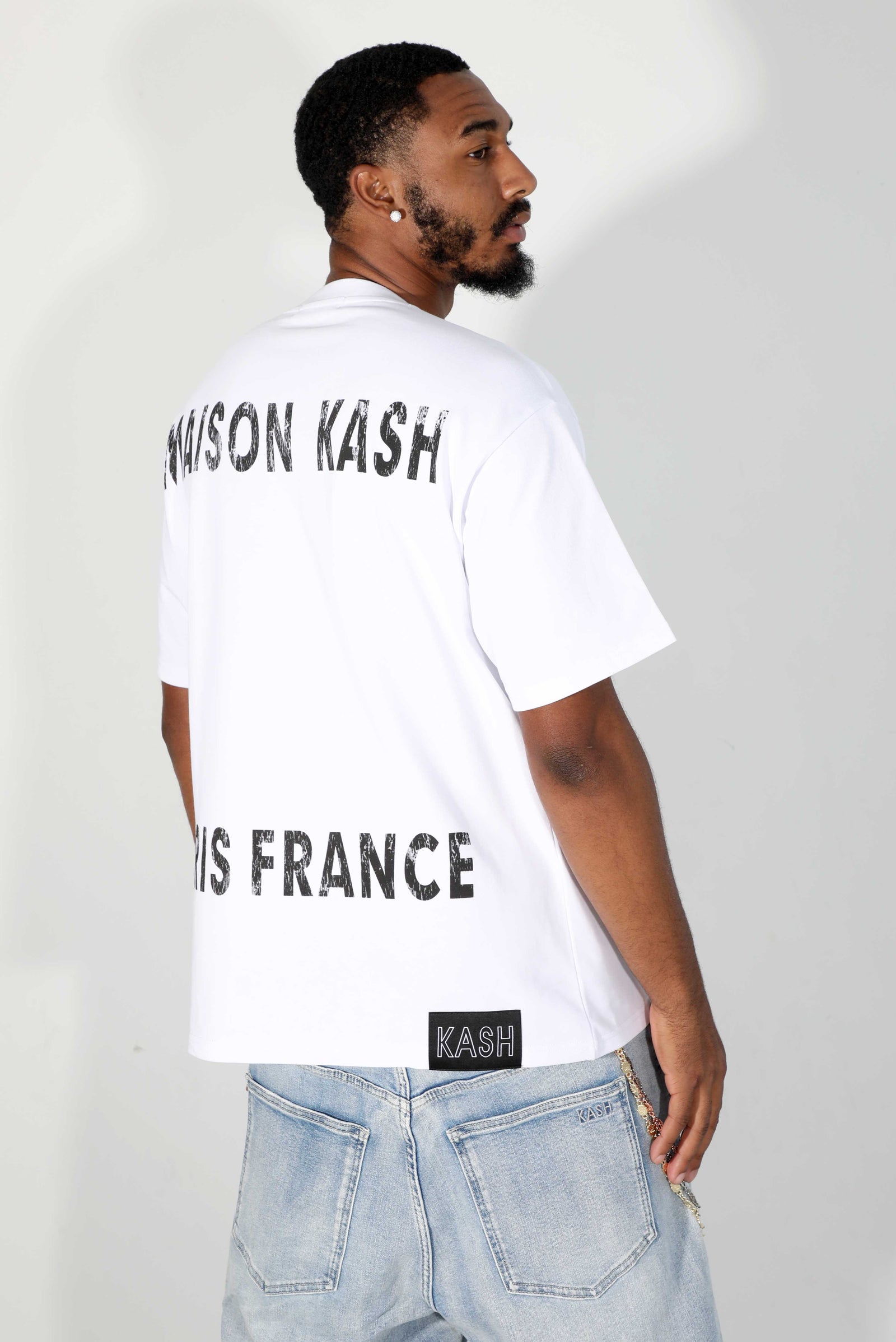 Model in light jeans showing the back of the white Maison Kash tee