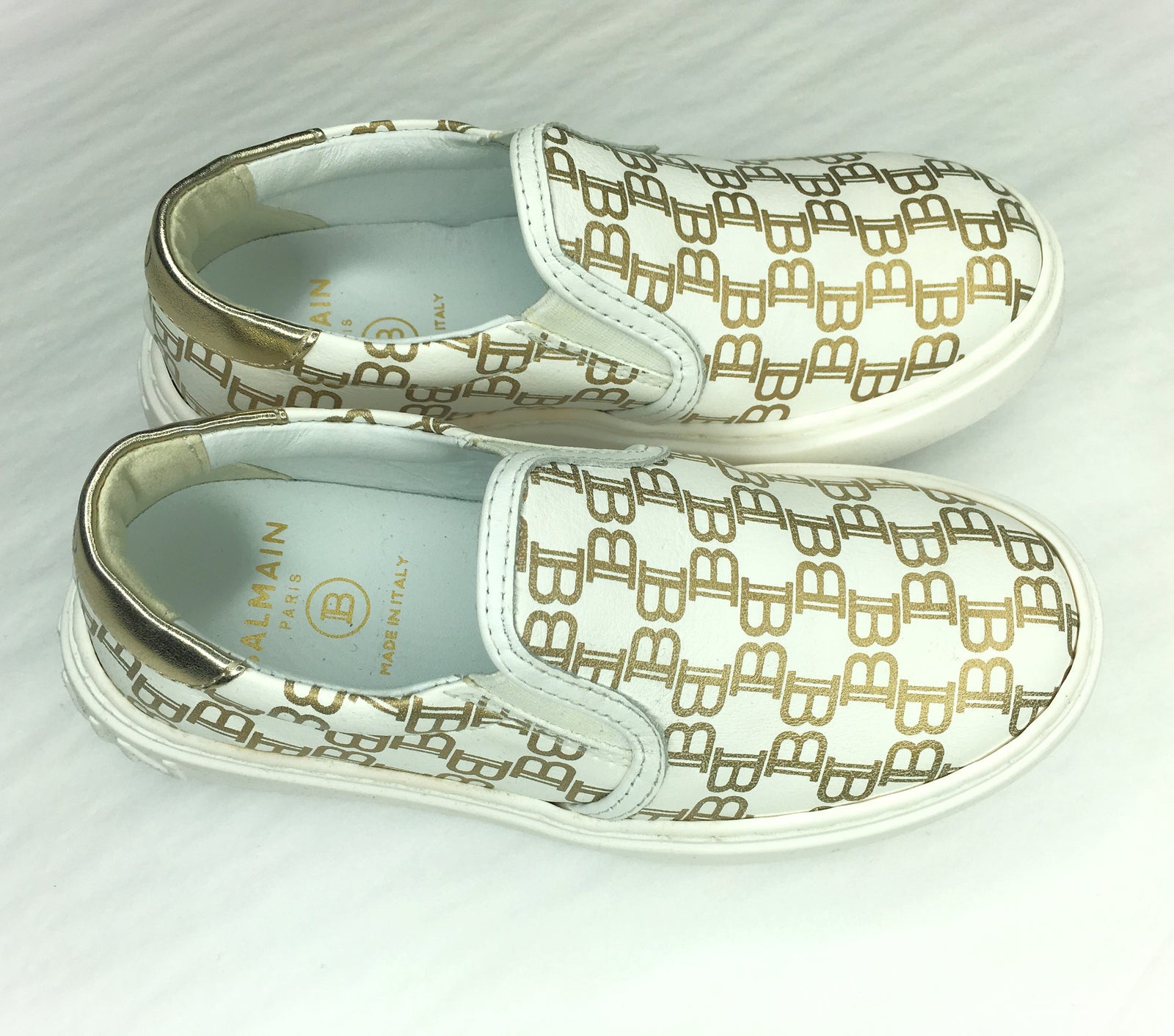 Balmain Kids Monogram All-Over Print Slip-On Trainers in white with gold – view 1 of 3