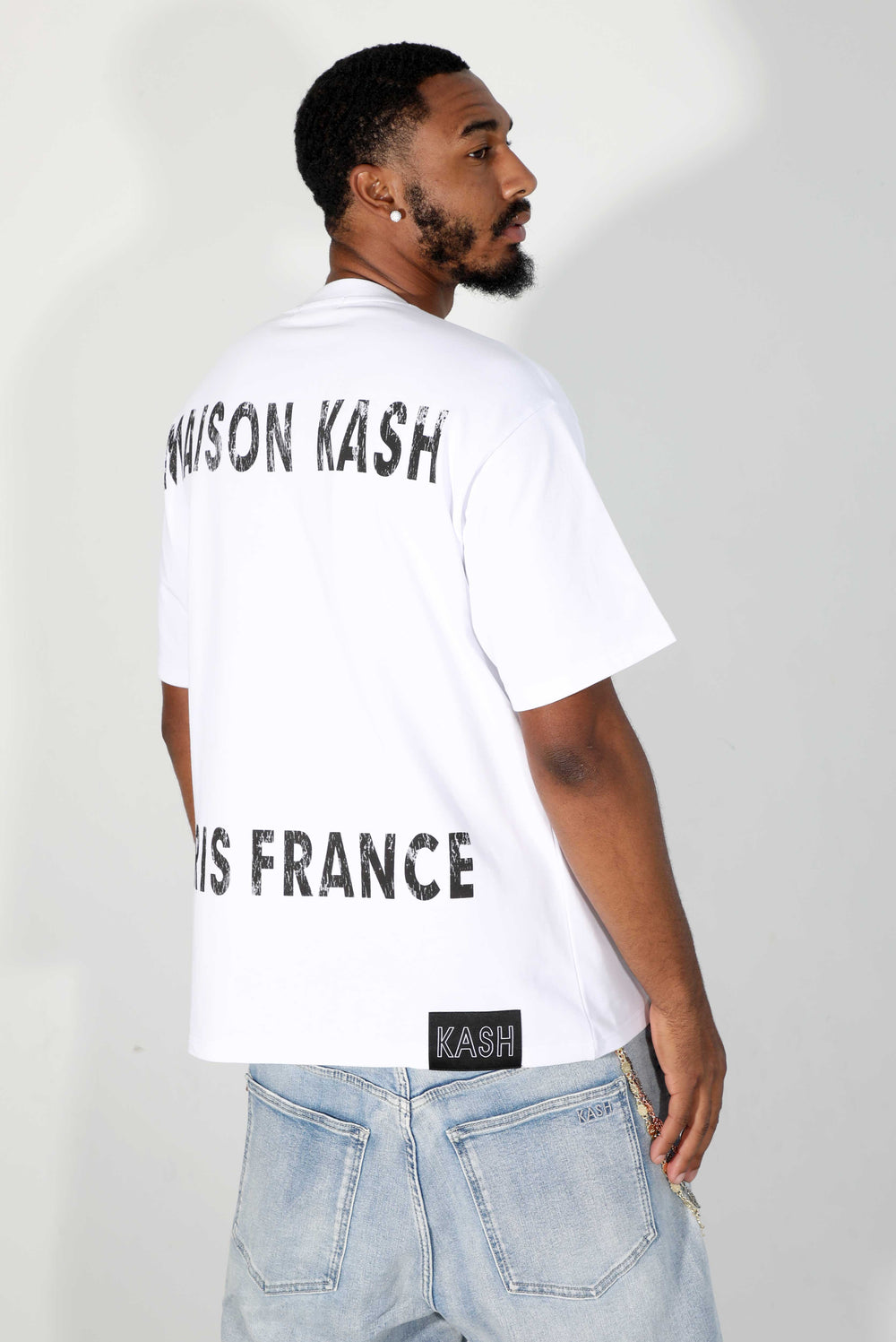 Model in light jeans showing the back of the white Maison Kash tee